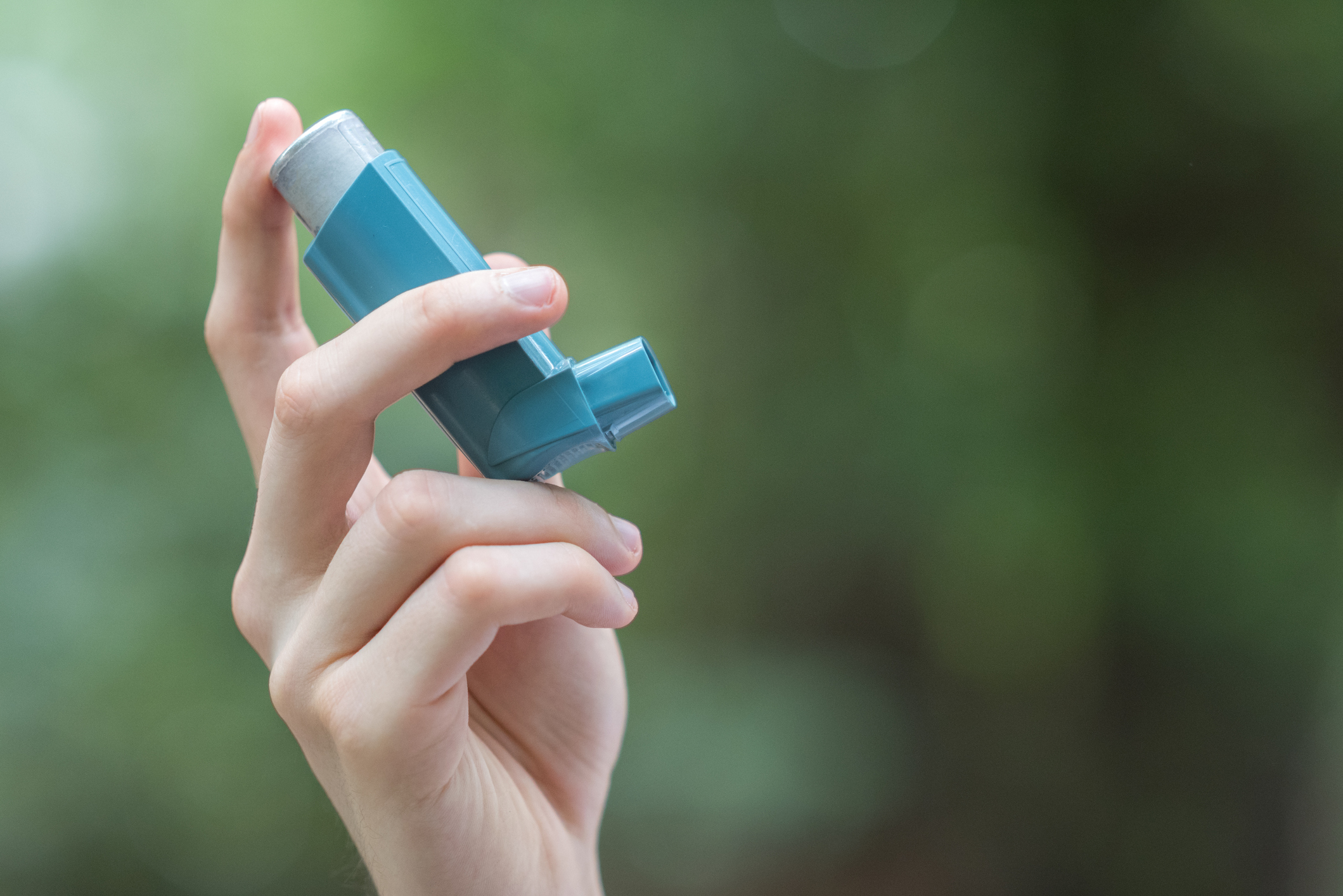 person holding a blue asthma inhaler